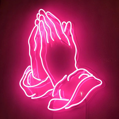 ink neon sign depicting a pair of praying hands on a dark background.